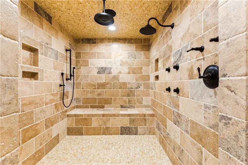 这是一个近距离观察宽敞的浏览淋浴区与黑色交手脱颖而出的米色色调的墙壁,地板和天花板。图片由Toptenrealestatedeals.com。
