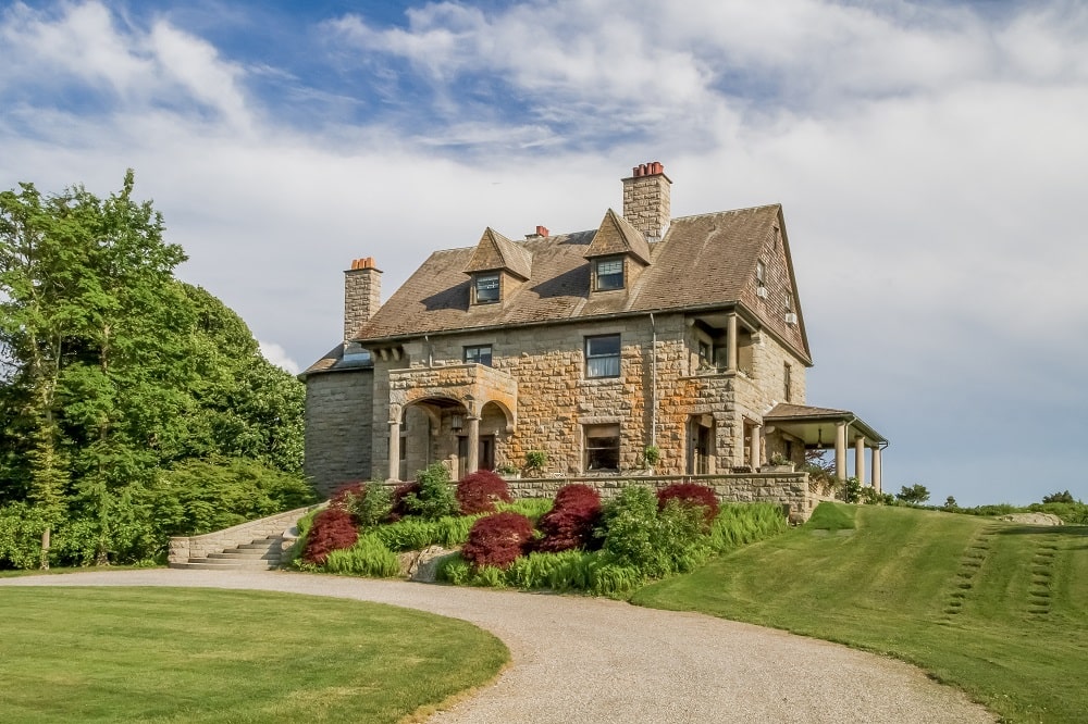 这是豪宅的外部景观，有装饰有天窗的花岗岩墙壁，高高的烟囱和一个色彩缤纷的花园。图片来自Toptenrealestatedeals.com。