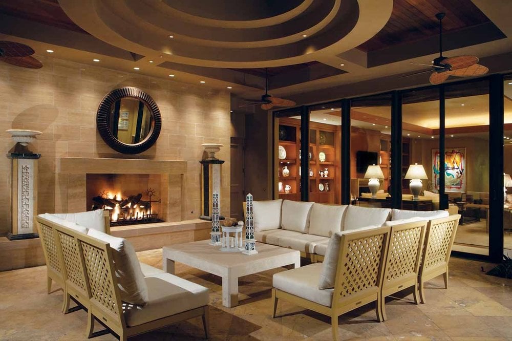这是一间带一座大壁炉的家庭娱乐室，壁炉上有一层米色壁炉幔，对面是装饰精美的天花板下的组合式沙发。图片来自Toptenrealestatedeals.com。