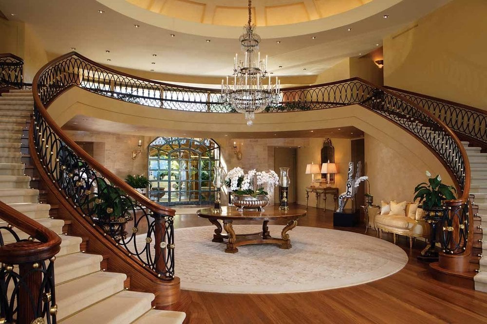 一进入豪宅，你就会被这个宏伟的门厅所欢迎，门厅里有弯曲的楼梯，高高的米黄色天花板，中间的木制圆桌上方悬挂着一盏吊灯。图片来自Toptenrealestatedeals.com。