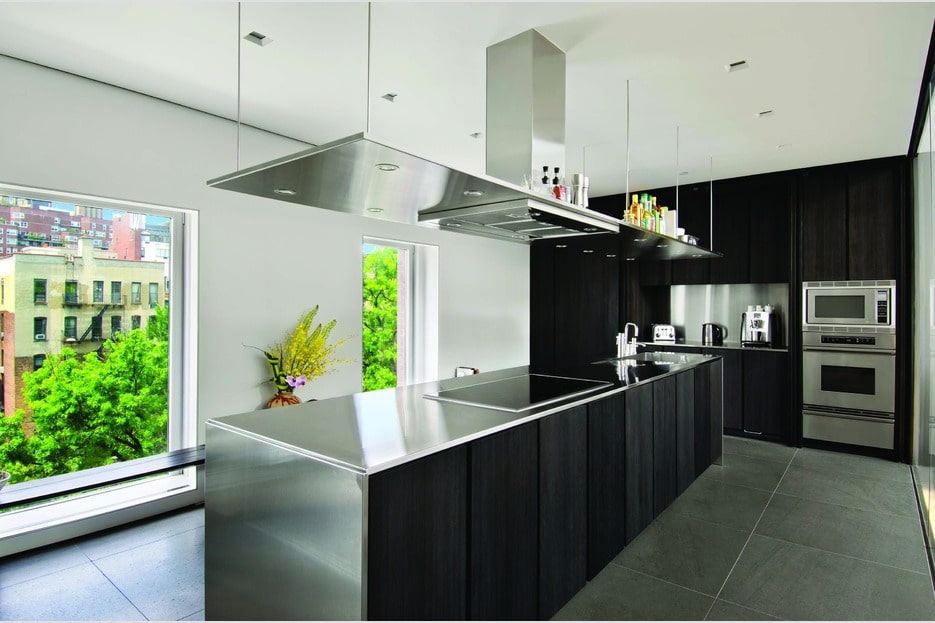 这个现代厨房有一个光滑的黑色厨房岛台，与远处的黑色墙壁和嵌入式橱柜相匹配。图片来自Toptenrealestatedeals.com。