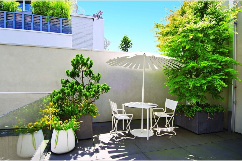这是另一个露台，配有室外用餐区，伞下装饰着盆栽植物。图片来自Toptenrealestatedeals.com。