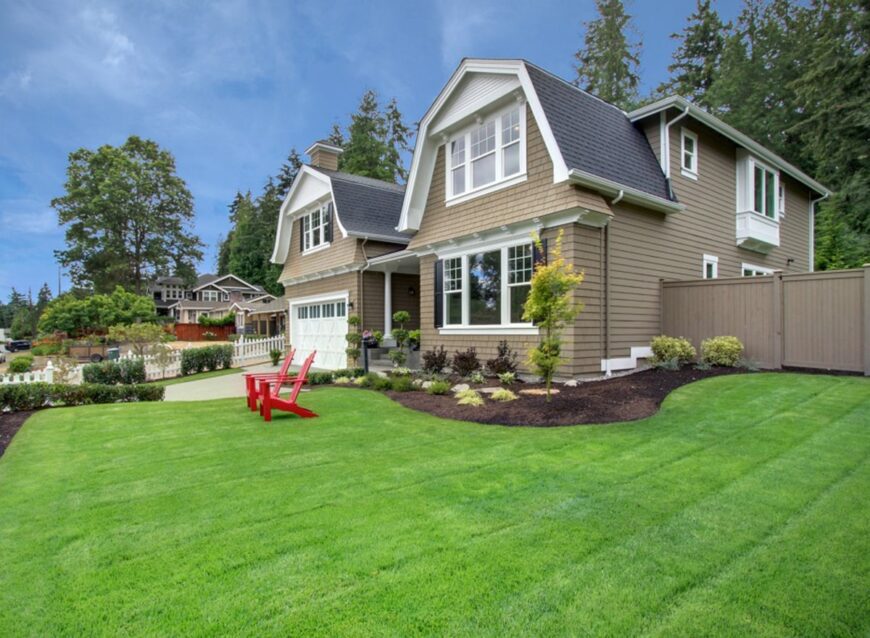 房子的侧视图展示宁静的景观和红色躺椅脱颖而出反对郁郁葱葱的绿色草坪。