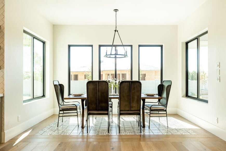 用餐室提供缓冲椅子和圆形吊灯照明的矩形餐桌。