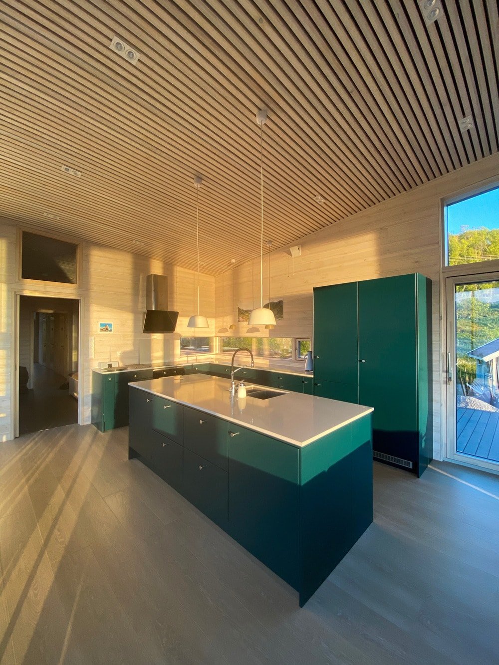这是从用餐区俯瞰厨房的全景。厨房橱柜的色调与墙壁和天花板的浅色木质元素形成鲜明对比。