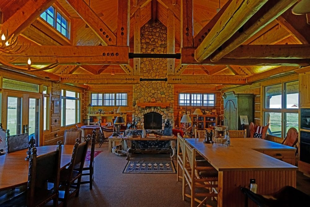 这是一个大房间的视图，客厅在远处，厨房和用餐区。这些都在高高的横梁天花板下。图片来自Toptenrealestatedeals.com。