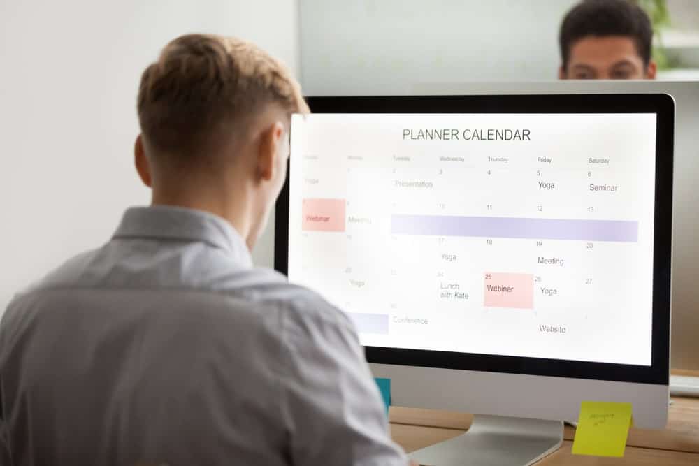 一位男性办公室职员正在用电脑在日历上记下重要事件。