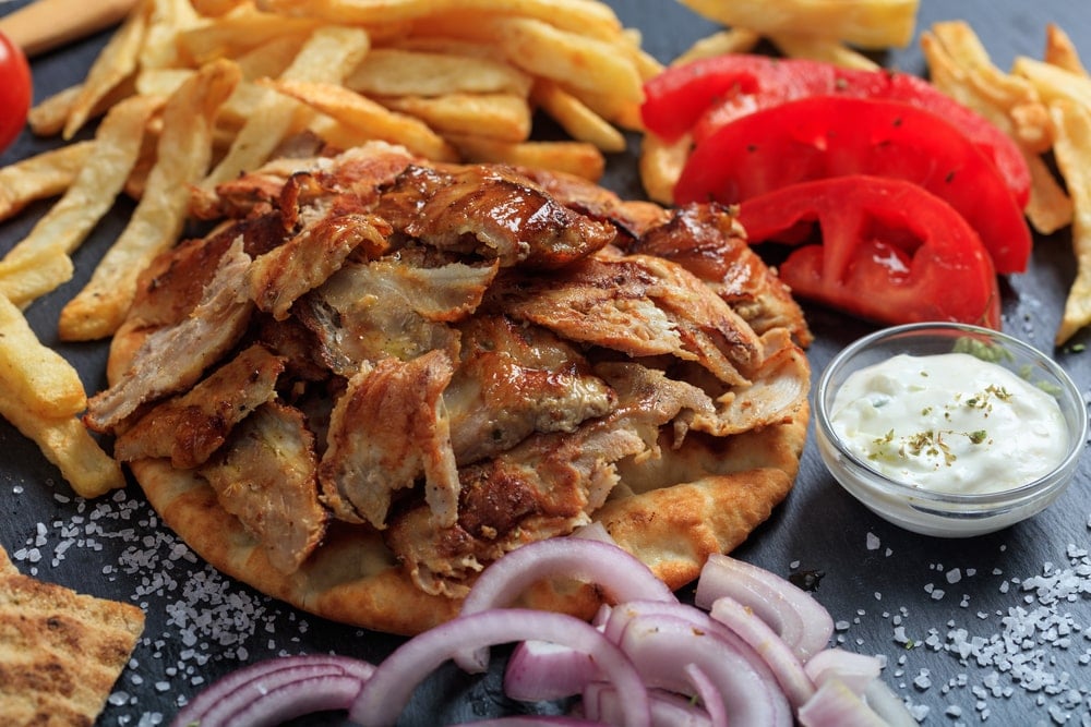 新鲜出炉的希腊陀螺配上薯条、新鲜番茄、洋葱和调味汁。
