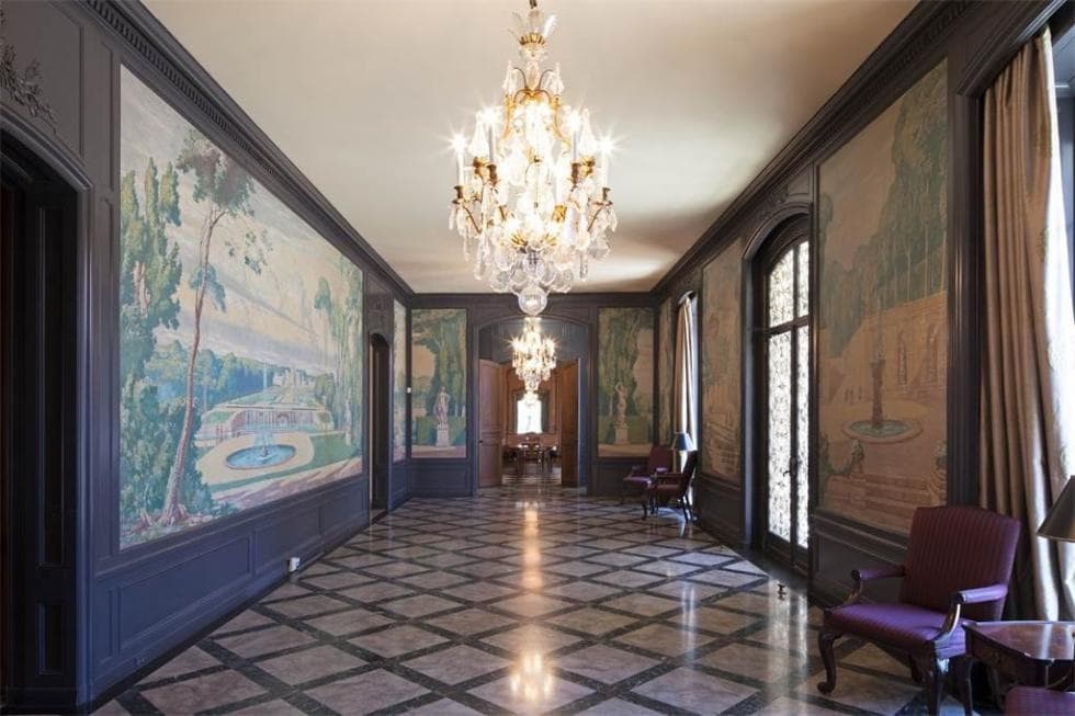 这是走廊，墙上有彩色的壁画，大理石地板上有格子图案，水晶吊灯与之相辅相成。图片来自Toptenrealestatedeals.com。