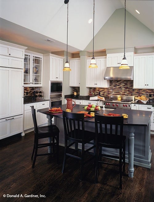厨房有白色橱柜，不锈钢电器，黑色花岗岩台面，和一个早餐岛。