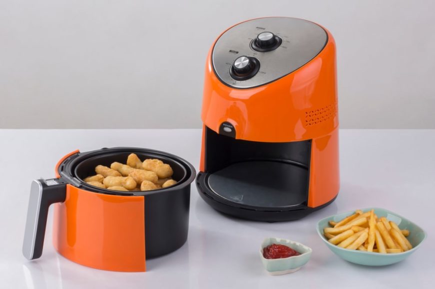一个鲜橙色的空气炸锅，里面有薯条和鸡块作为样品。