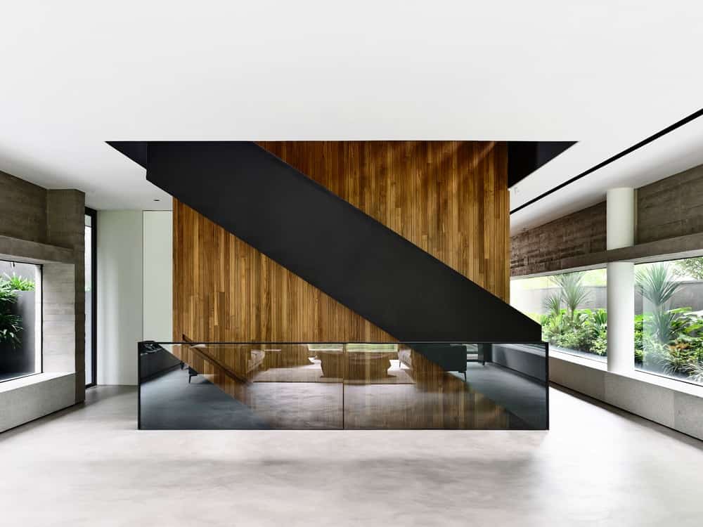 这是二楼平台的外观，黑色楼梯搭配不透明的玻璃栏杆，与木板墙和玻璃墙形成独特的组合。