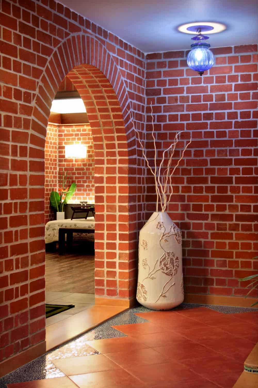 这是砖的拱形入口进卧室装饰着一个大花瓶和一个现代的照明。