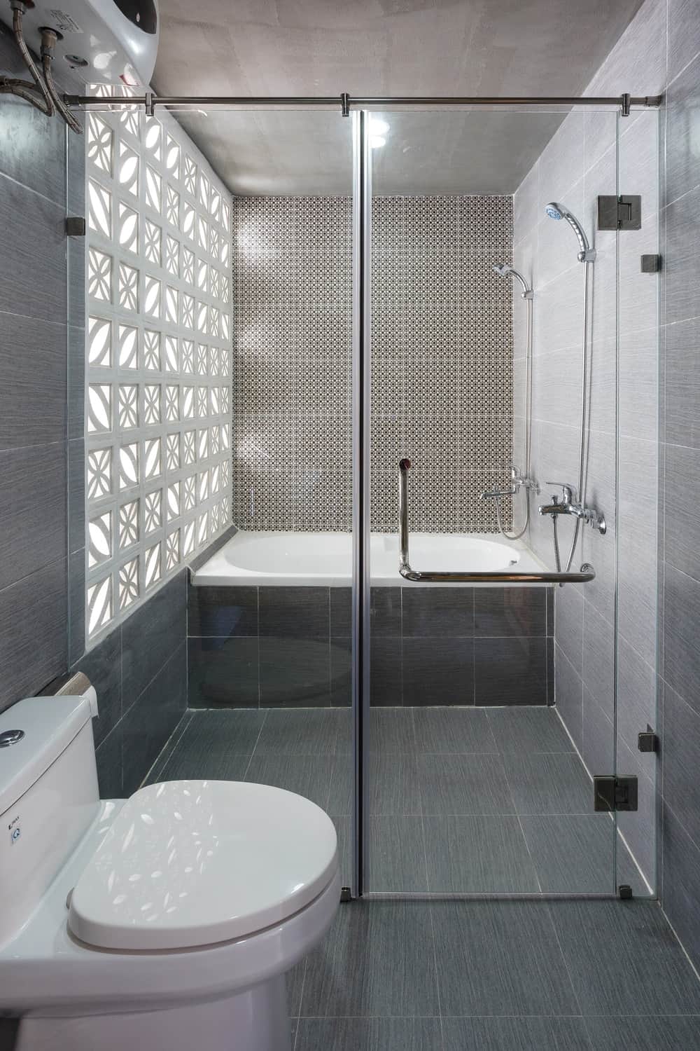 厕所的一侧是通往浴室湿侧的玻璃入口，浴室的远端有淋浴区和浴缸。