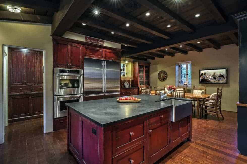 这是一间宽敞的厨房，有高高的横梁天花板，里面有嵌壁灯。这与红木橱柜相搭配，使不锈钢电器脱颖而出。图片来自Toptenrealestatedeals.com。