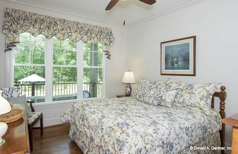 这间卧室有白墙、木制家具，还有一扇可以俯瞰后门廊的大窗户。