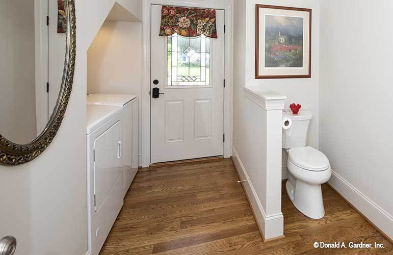 浴室里有白色的橱柜，厕所区装饰着一幅装裱好的艺术品。