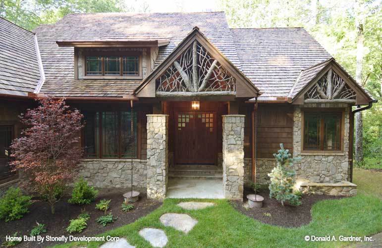 住宅立面有一个棚屋天窗，石头口音，木制双前门，山墙屋顶装饰着装饰性的乡村装饰。