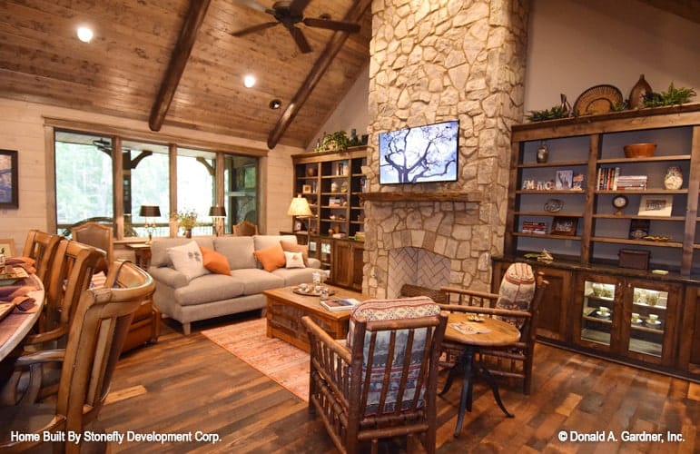 客厅里有一座石砌壁炉、深色木质嵌壁式家具、灰色组合家具、软垫椅和木桌。