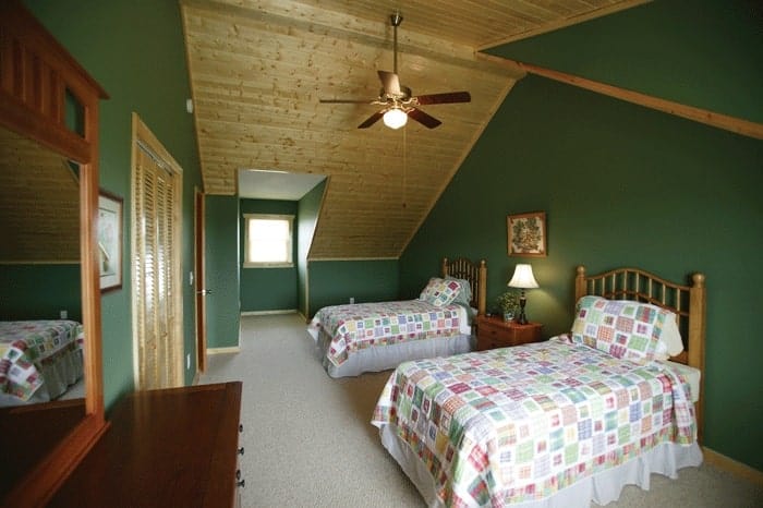 卧室有拱形天花板，绿色墙壁，地毯地板，和两张床。