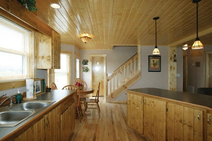 这间可用餐的厨房里有几个木橱柜、一个双碗水槽和一个早餐吧台。