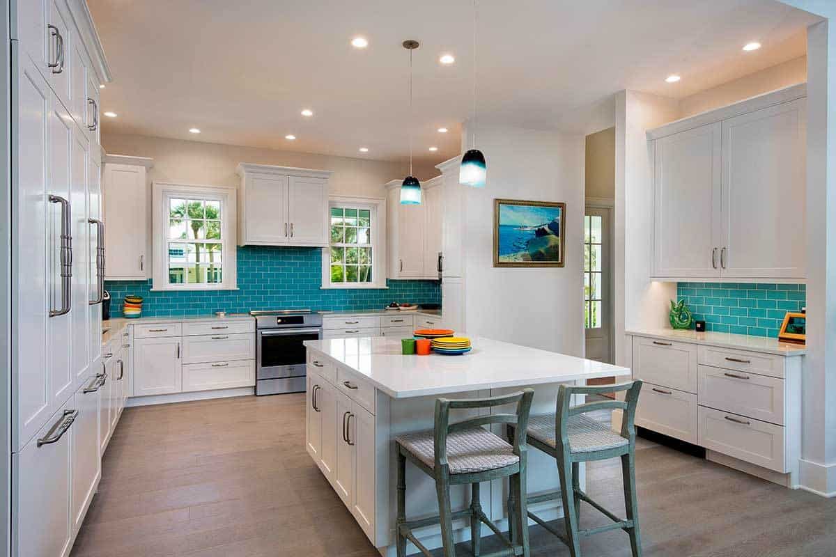 厨房配备了大理石台面、白色橱柜、早餐岛和蓝色地铁瓷砖后挡板，为该地区增添了一抹色彩。