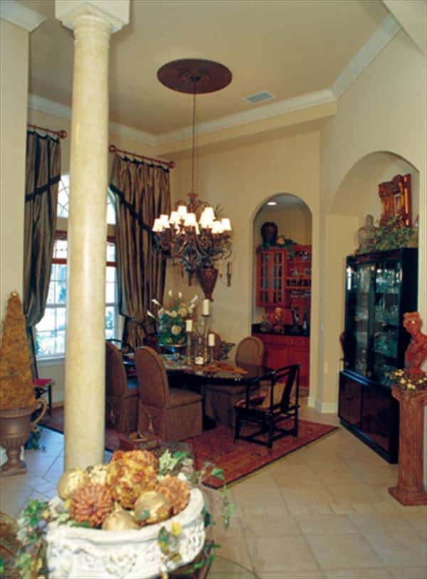 餐厅有一个拱形的窗户,椭圆形餐厅集,和一个黑色显示内阁对拱形嵌入墙放置。