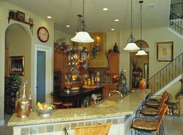 厨房配有双层岛酒吧,木制的橱柜,花岗岩台面,玻璃穹顶吊坠。
