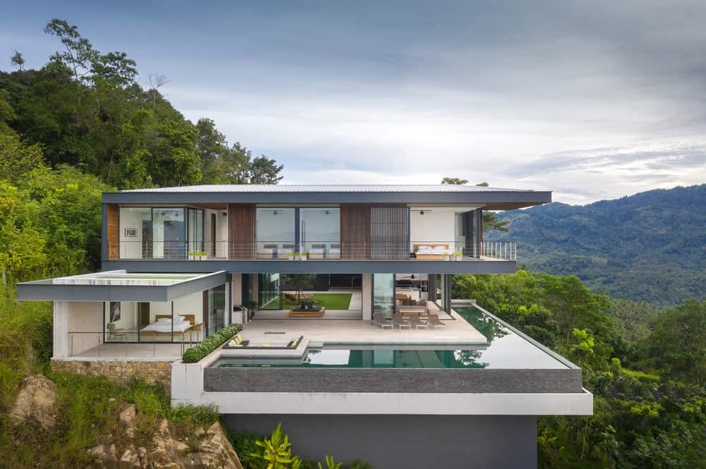 这是房子的鸟瞰图，它有一个现代的设计，辅以玻璃墙和面向悬崖的露台以及无边泳池。