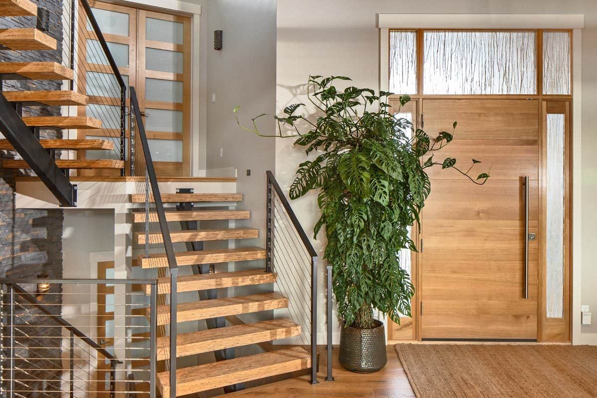 门厅里有一座现代化的楼梯、一株高大的盆栽和一块黄麻地毯。