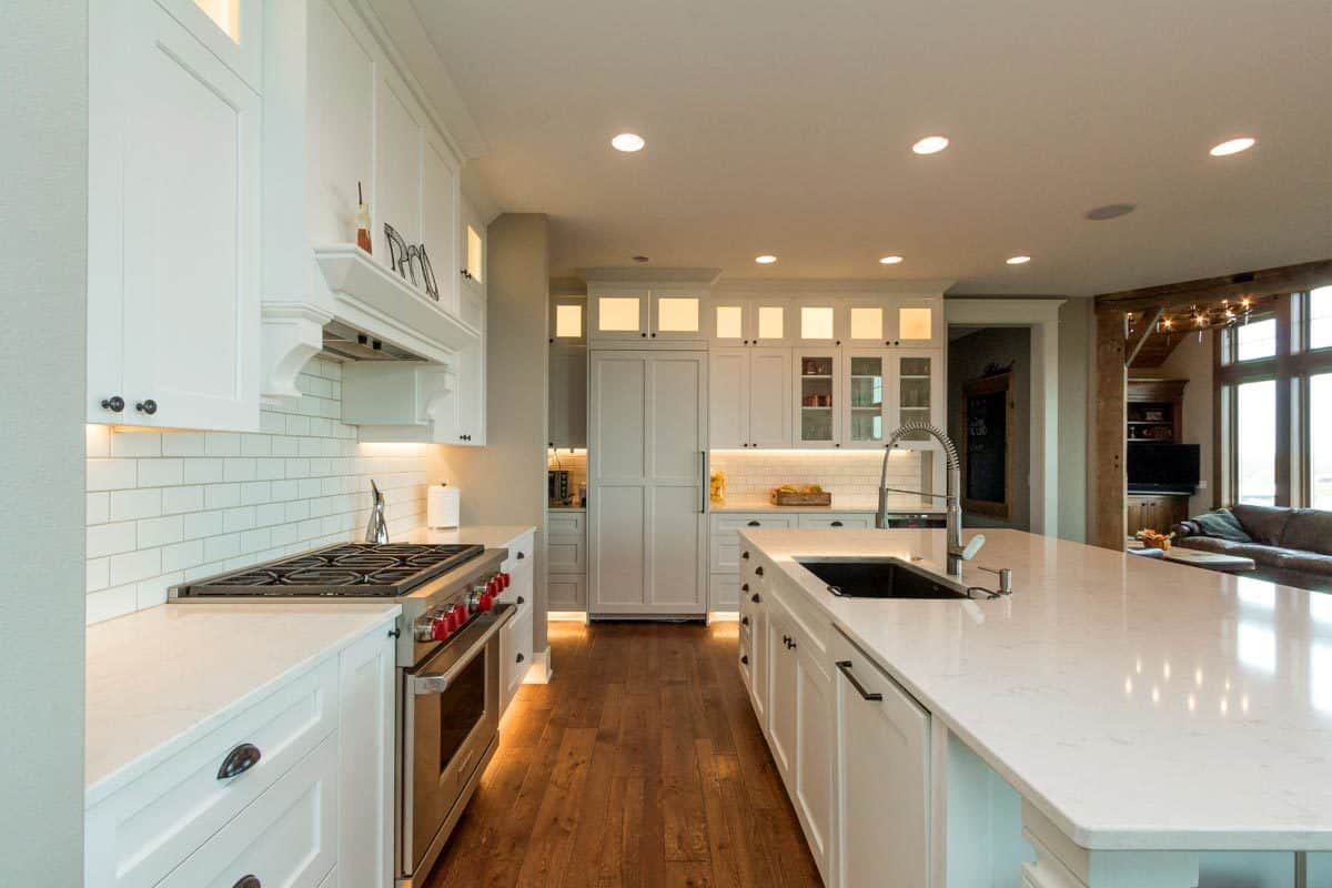 宽阔的木板地板为白色厨房创造了舒适和对比鲜明的外观。