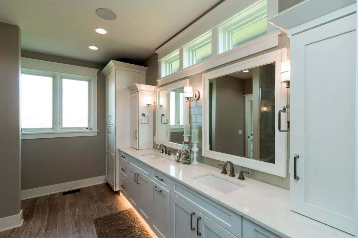 主浴室设有一个大型双水槽梳妆台，大理石台面，白色镜框镜子，玻璃烛台和黄铜固定装置。