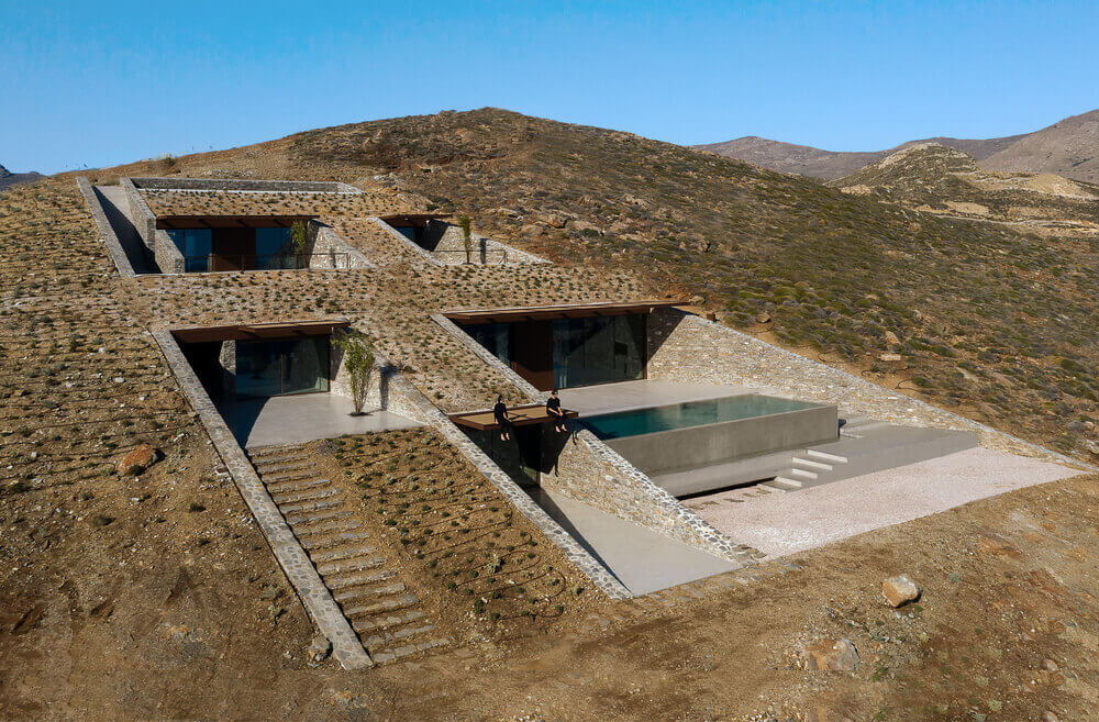 这是房子的外观，它嵌入悬崖的一边，俯瞰着海洋，用土砖结构和混凝土台阶。