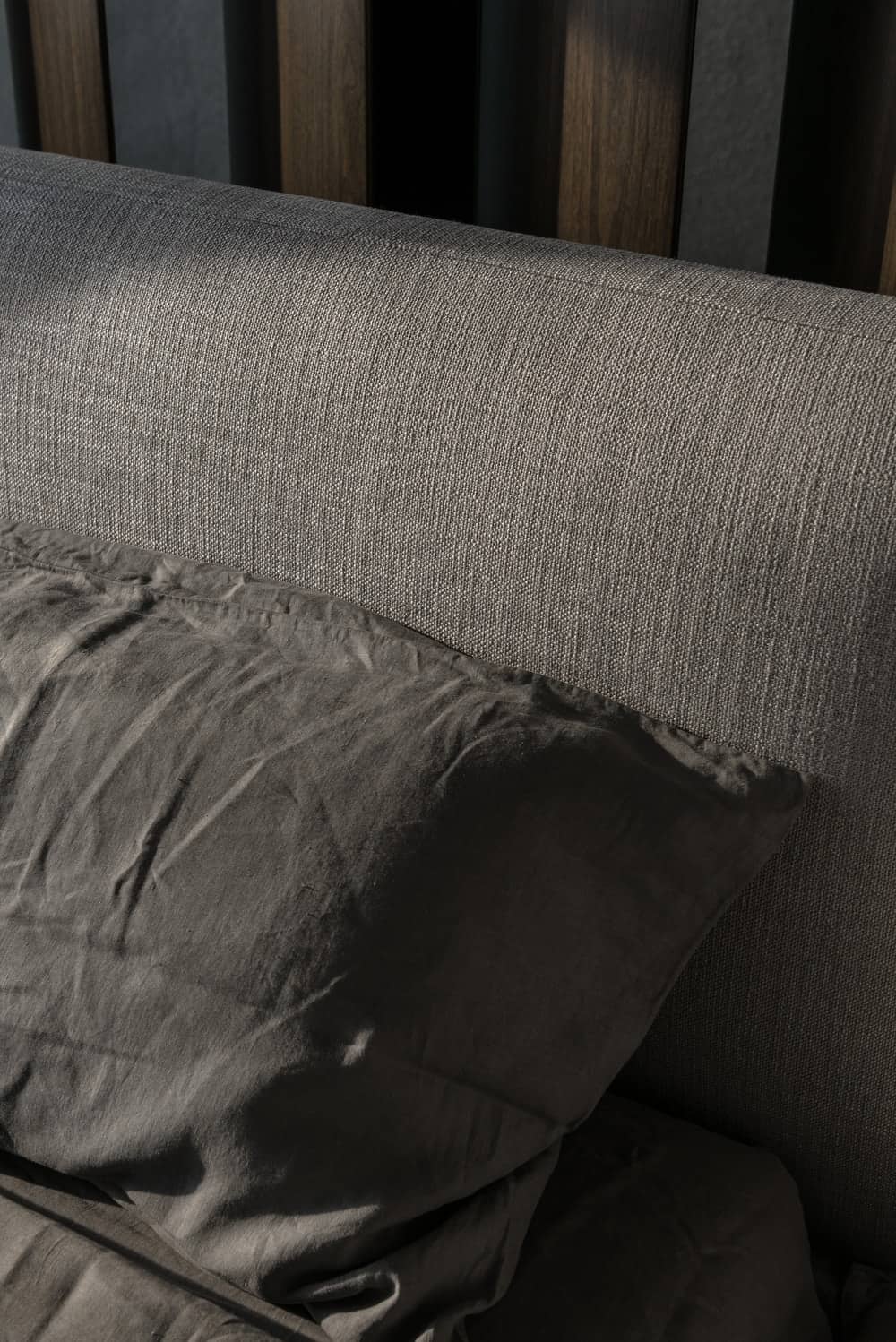 这是一个仔细观察的灰色软垫床头板的床与配套的灰色枕头。
