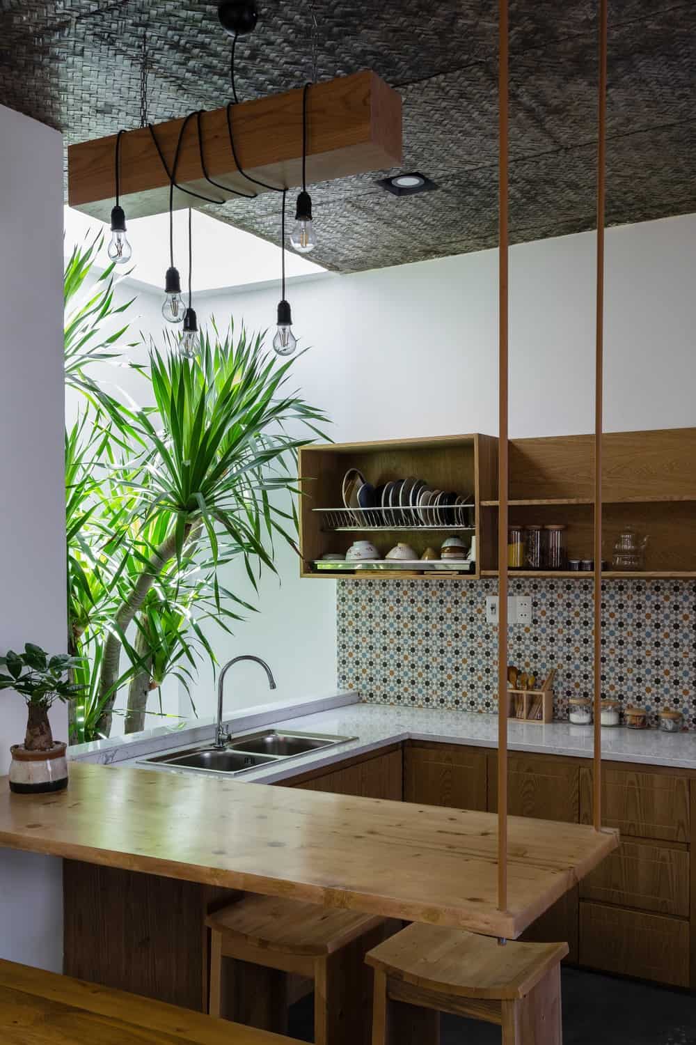 从厨房的视角可以看出，附属的木桌由几根细柱悬挂在天花板上，顶部装有木制照明灯具。