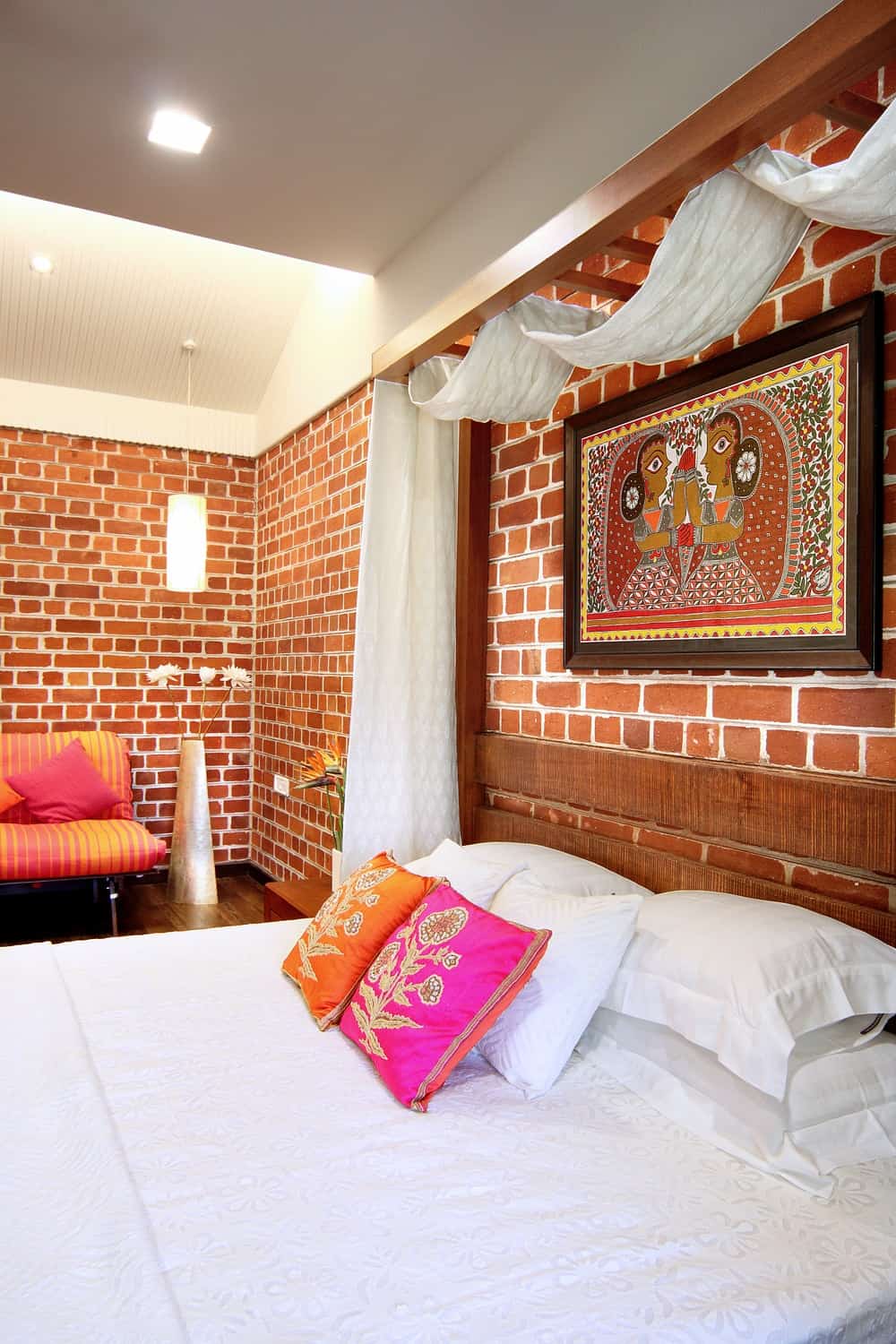 这个卧室有一个木制的床顶部有一个丰富多彩的绘画高于木床头板和坐在面积。