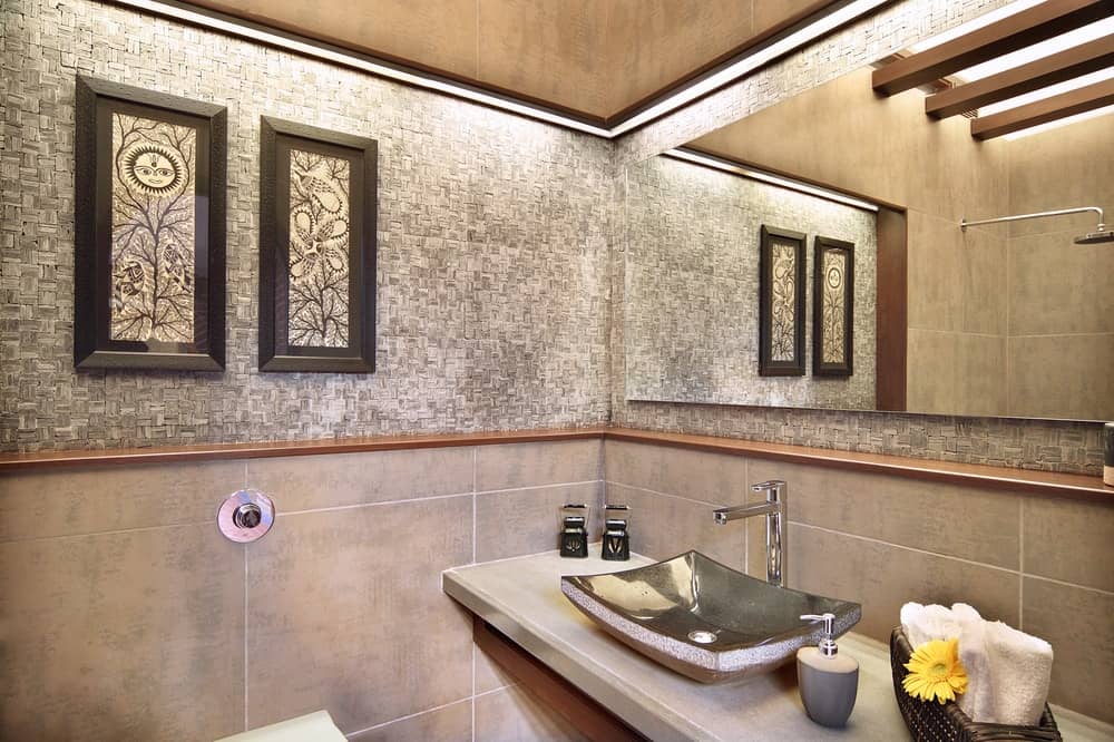 浴室有一个朴实的灰色基调的瓷砖和墙。它也有一个浮动的虚荣与独立式水槽下面一个大玻璃镜子。