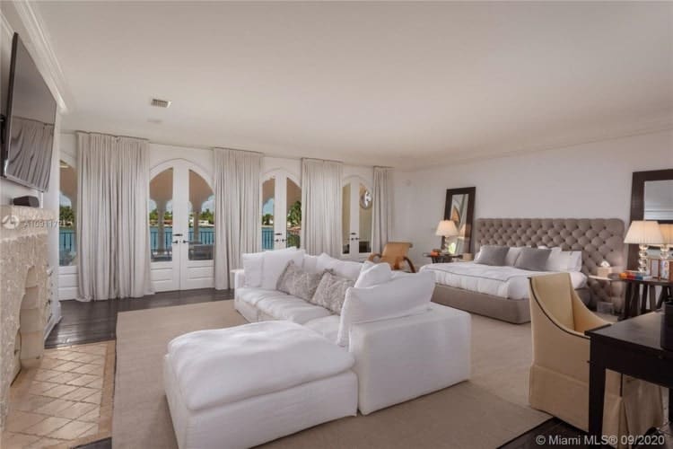 主卧室有一个簇绒床和一个大的白色的l形截面在对面沙发上坐着。图片由Toptenrealestatedeals.com。