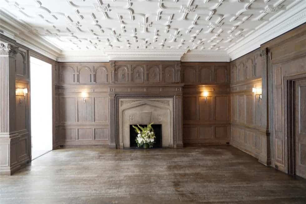这是一间宽敞的额外房间，墙壁镶着木板，天花板是白色的图案，壁炉的另一侧有木制的壁炉架。图片来自Toptenrealestatedeals.com。