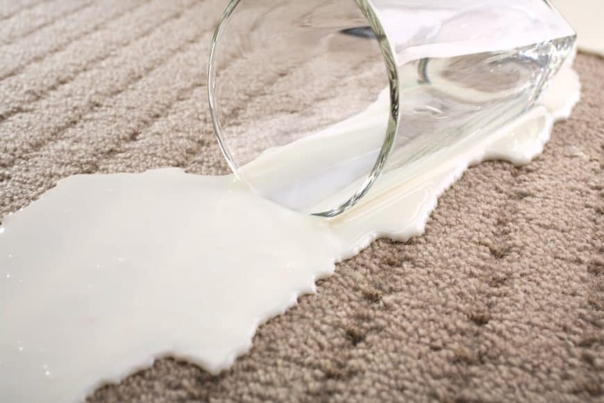 牛奶从地毯上的杯子里溢出来。