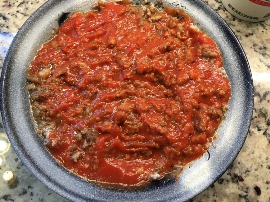 把意大利面酱和熟肉放在平底锅里。