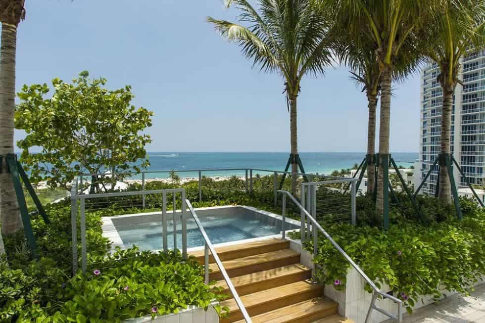 大露台的这一部分有一个温泉式的游泳池，周围环绕着热带灌木和树木，可以看到远处的海滩。图片来自Toptenrealestatedeals.com。