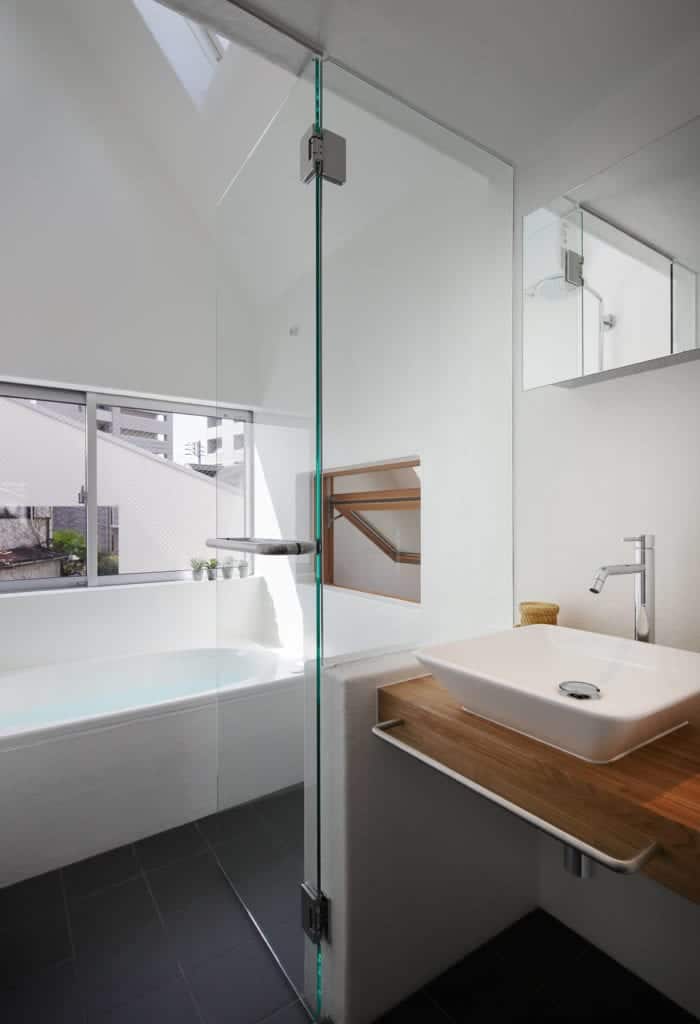 这间现代化的浴室里有一个浴缸和一个用半面玻璃墙隔开的浮动水槽。