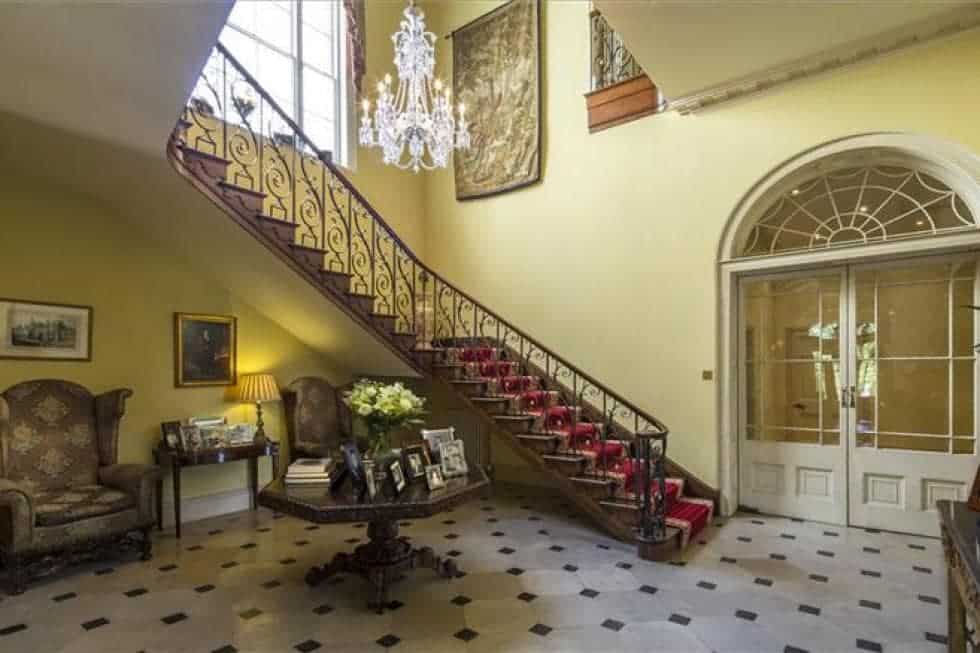 在进入主庄园时，你会受到这个优雅的门厅的欢迎，这里有弯曲的楼梯，圆形的木桌和米黄色墙壁的水晶吊灯。图片来自Toptenrealestatedeals.com。