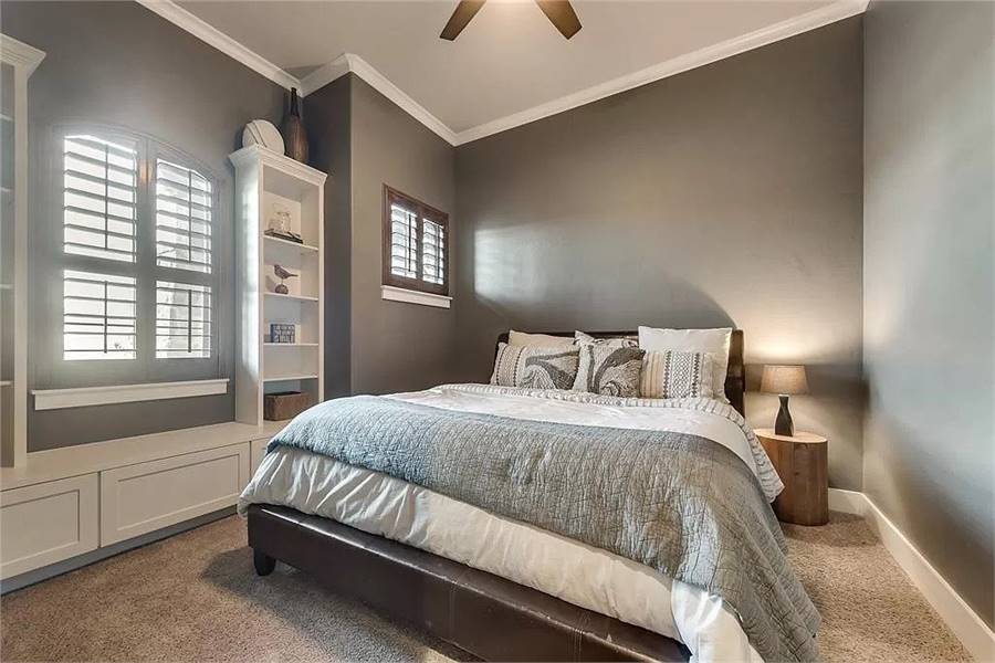 这间卧室有灰色的墙壁，地毯地板，靠窗的座位和一张舒适的床。
