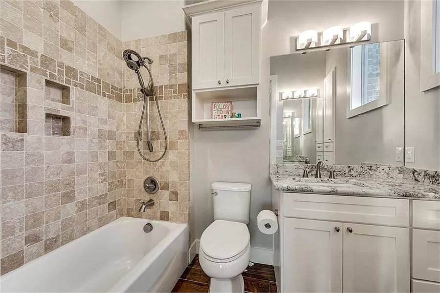 浴室有白色梳妆台，马桶，浴缸和淋浴组合。