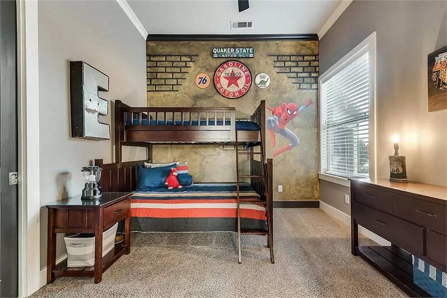 这间卧室里有一张双层床、几个木柜和一面装饰着蜘蛛侠壁画的强调墙。