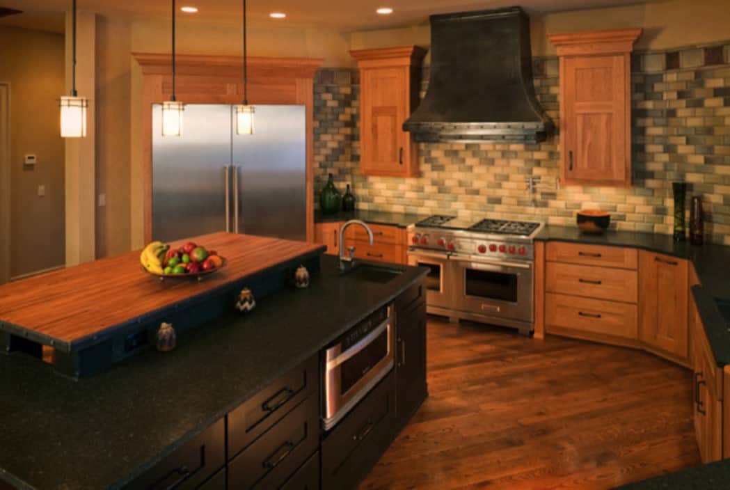 厨房配有不锈钢用具，线性马赛克瓷砖后挡板，黑色花岗岩台面，和一个两层岛。