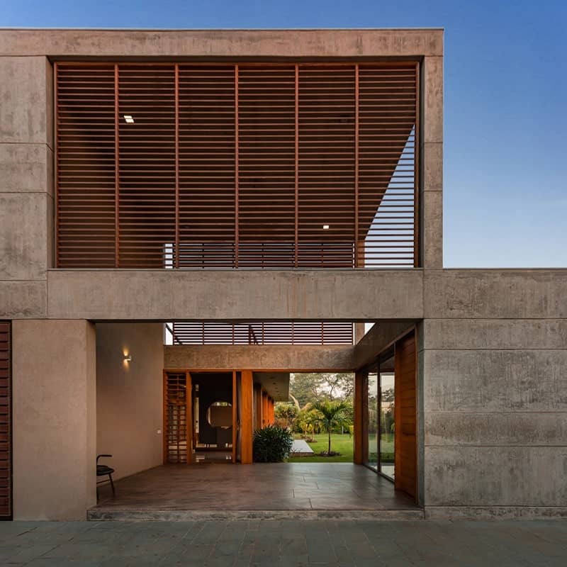 这是房子的正面视图，展示了混凝土结构，支撑着二层的透明木板。