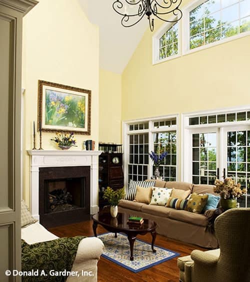 客厅里有舒适的布制座椅、一座壁炉、几扇高窗，还有一张放在镶边地毯上的深色木咖啡桌。
